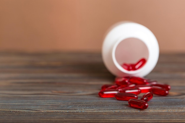 알약 병 주위에 엎질러진 빨간 알약 의약품 및 처방약은 평평한 배경 빨간색 의료 캡슐