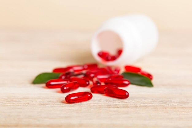 薬瓶の周りにこぼれた赤い錠剤薬と処方薬フラットレイ背景赤い医療カプセル