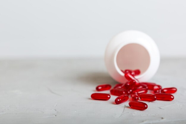 Red pills spilled around a pill bottle Medicines and prescription pills flat lay background Red medical capsules