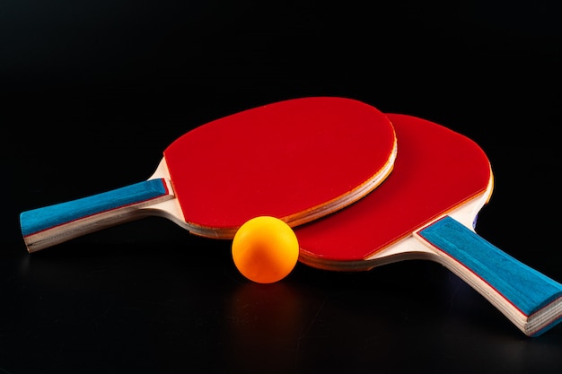 Red ping pong racket on dark surface