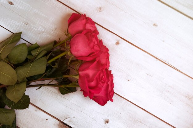 Bouquet di rose rosa rosso su una superficie di legno