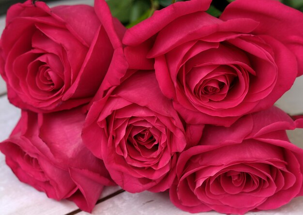 木製の表面にバラの赤ピンクの花束