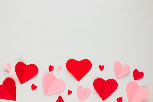 발렌타인 데이를 위한 배경 배너나 엽서의 프레임 테두리에 평평하게 놓인 빨간색과 분홍색 종이 하트 모양