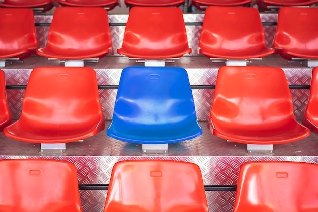 Red plastic chairs with blue seats in the middle.Concept the courage to be different.