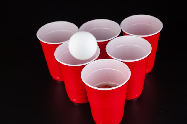 Red plastic cups and ball for game of beer pong