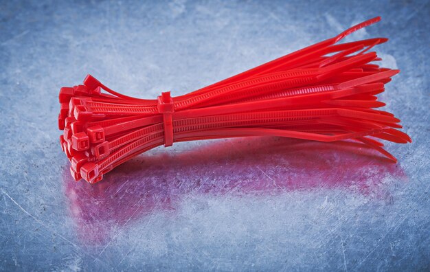 Red plastic selflocking cable ties on metallic background construction concept