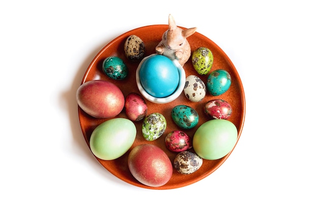 Photo a red plate with an easter bunny and colored chicken eggs and quail eggs