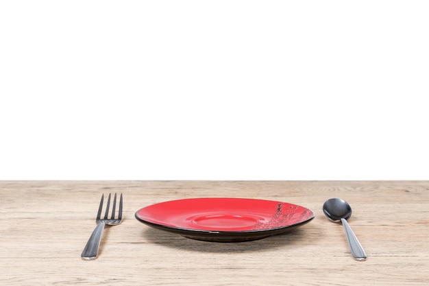 Красная тарелка с иероглифами и рядом с металлической вилкой и ложкой на деревянном столе, старом изолированном на белом фоне