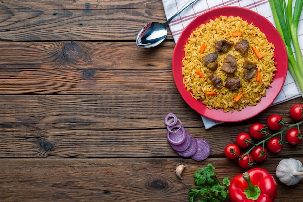 Red plate with pilaf on a white wooden table background with copysapce. Top view