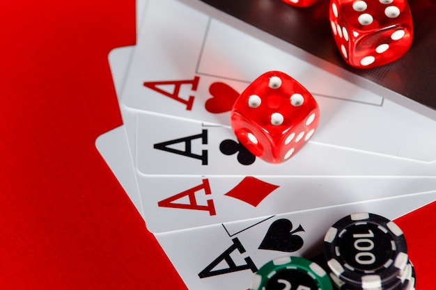 Red playing dice and cards with aces close-up.