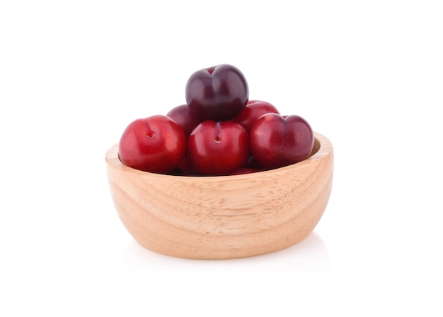 Red plum fruit isolated in wooden bowl on white surface