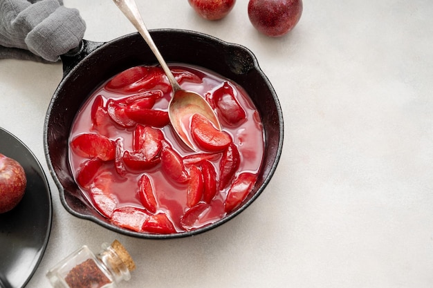 Red plums confiture or jam Cooking fresh fruit sauce in black pan Copy space