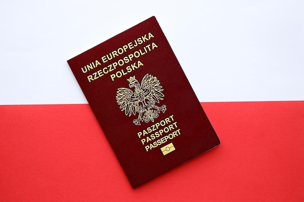 Красный польский паспорт на гладком красно-белом флаге Польши вблизи