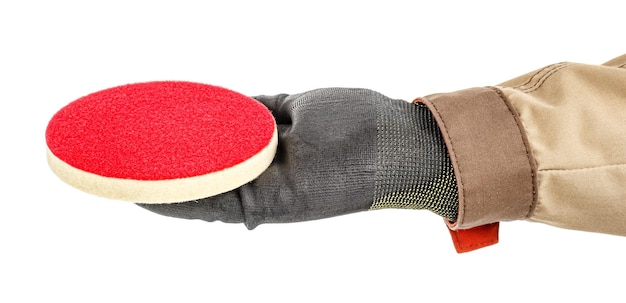 Red polishing disc lies in palm of male hand in black protective glove isolated on white