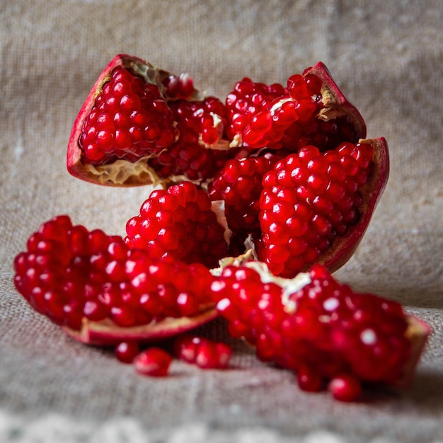 Red pomegranate fruit on canvas Whole fruit and its grains Square format