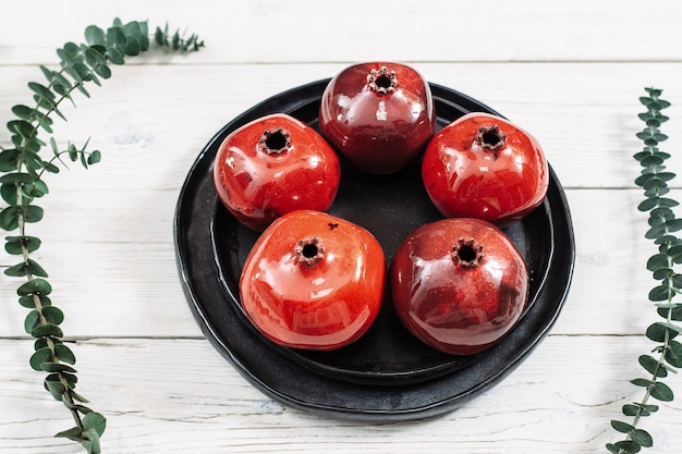 Red pomegranates on ceramic plate and floral decor