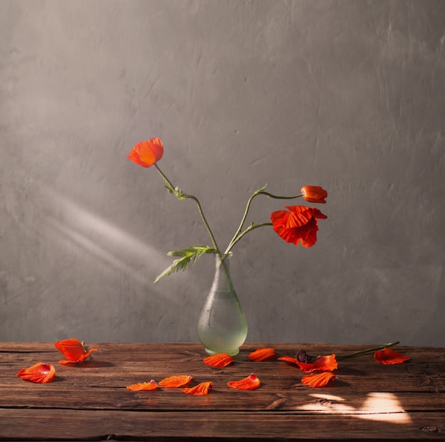 Red poppies in vase on wooden table