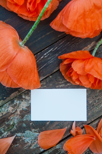 Red poppies on wooden backdrop with empty space white business card mockup