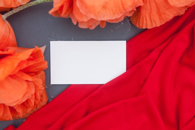 Red poppies on wooden table with empty space white business card