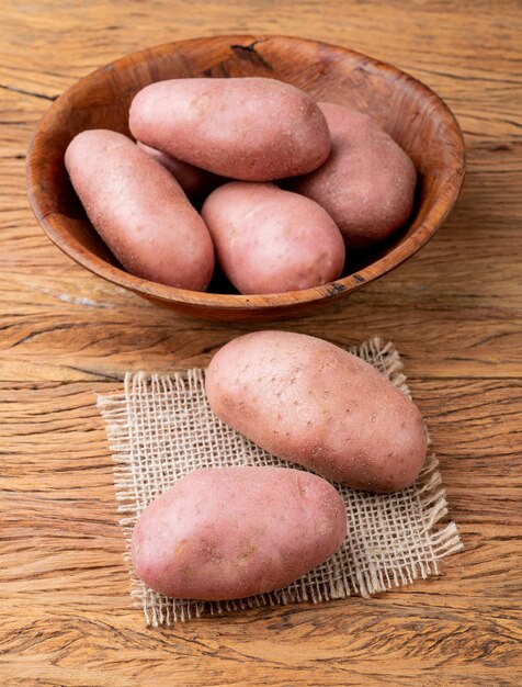 Red potato in a bowl over wooden table.