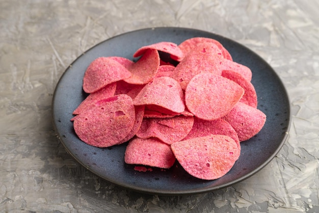 Red potato chips on gray concrete background Side view close up