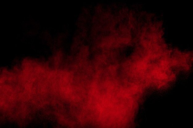 Red powder explosion on black background. Freeze motion of red dust particles splash.