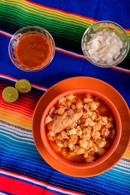 Foto pozole rosso servito in un piatto profondo su serape colorato cibo tipico messicano fatto di mais