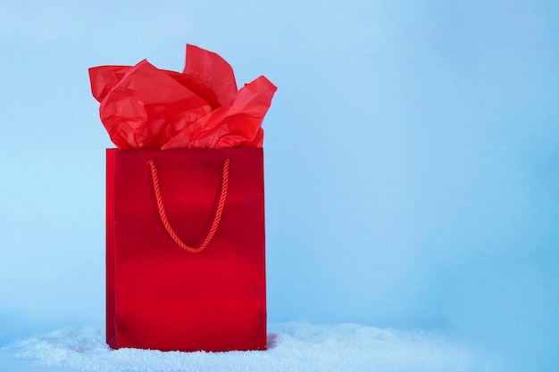 Red present bag on snow and light blue background