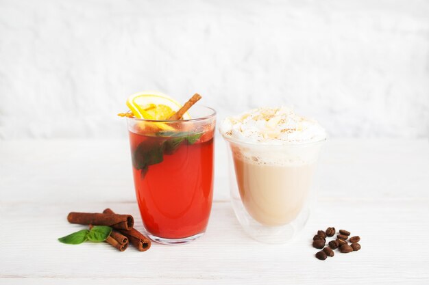 Red punch and latte in glasses on white