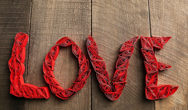 Photo red quilling word love on wooden background