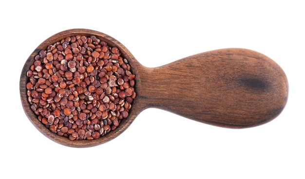 Red quinoa seeds in wooden spoon isolated on white background Pile of raw kinwa Top view