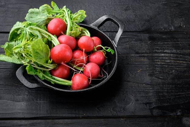 Red radish bunch with green leaves set, on black wooden table table