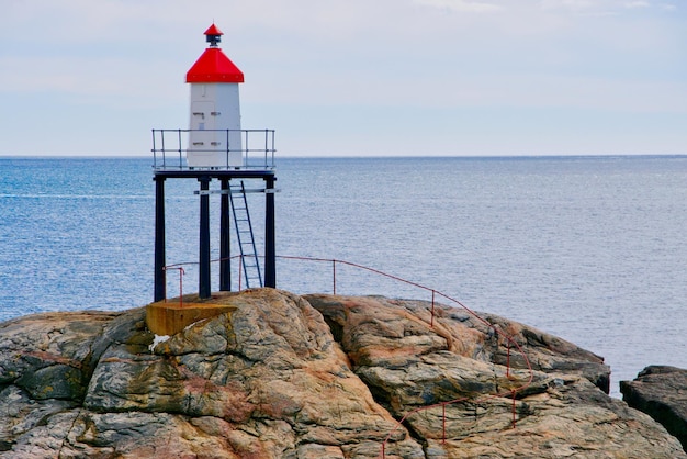 Photo red railing on a rock with a lighthouse