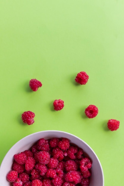 Photo red raspberry berry in plate on green table fruit berries background summer fooddiet vitamin and vegan food organic natural and healthy snackcopy space