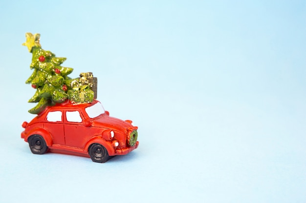 Red retro car carries a Christmas tree with gift boxes on the roof