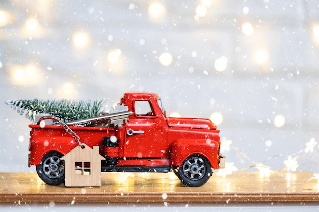 Red retro car with a Christmas tree decorates with the house key in the pickup truck for Christmas Buying a home moving mortgage loan real estate festive mood New Year