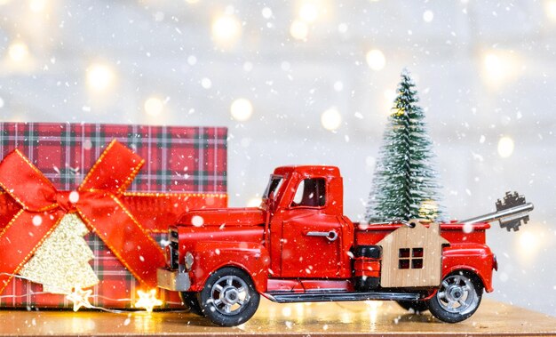 Red retro car with a Christmas tree decorates with the house key in the pickup truck for Christmas Buying a home moving mortgage loan real estate festive mood New Year