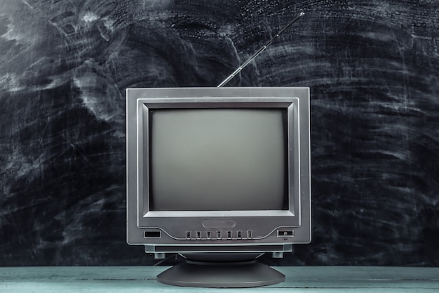 Red retro old school portable mini tv set on blackboard background