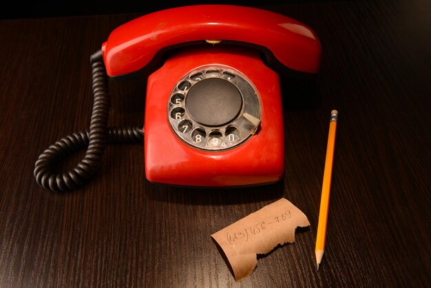 Red retro telephoneon dark wooden background