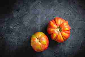 Photo red ribbed tomato cuore di bue on a dark background top view