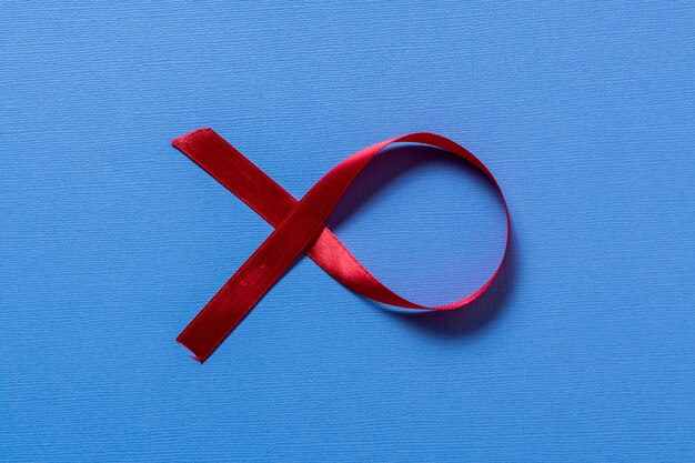 Red ribbon breast cancer awarerness on blue background and copy space for text.