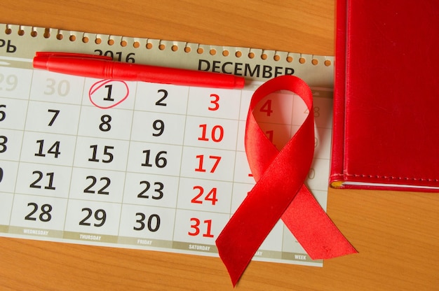 Nastro rosso sul calendario per aumentare la consapevolezza contro lo spazio della copia dell'aids