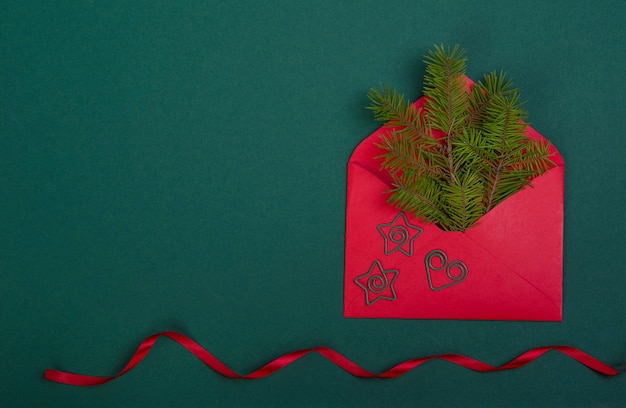 Red ribbon, next to an envelope with a Christmas tree branch.