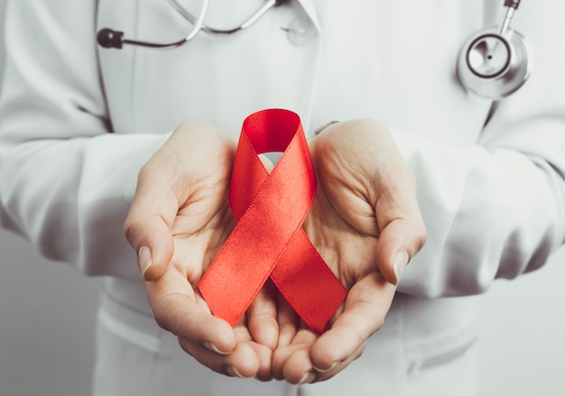 Red ribbon in the hands of a doctor as a symbol of World Aids Day. 