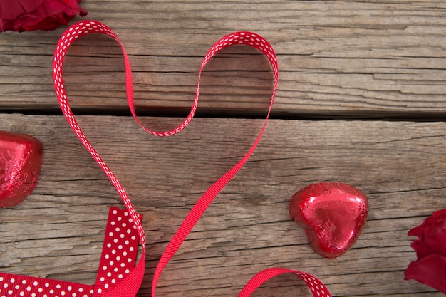 Red ribbon in heart shape and decoration on wooden surface