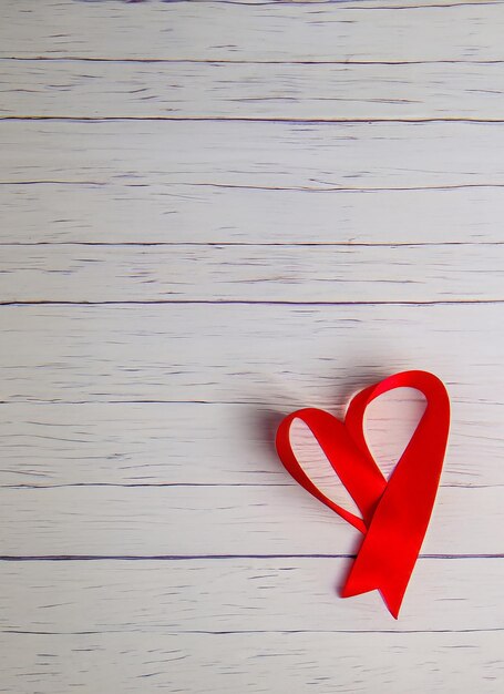 Red ribbon heart on a white wooden background in a romantic valentine day family or wedding