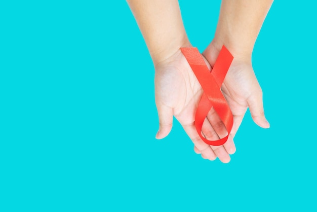 red ribbon in hold hand on isolate of aqua blue background