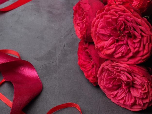 A red ribbon is next to a bouquet of red roses.