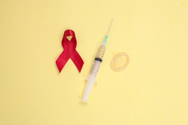 黄色の背景に分離されたHIVに対する赤いリボンと医療機器のシンボル