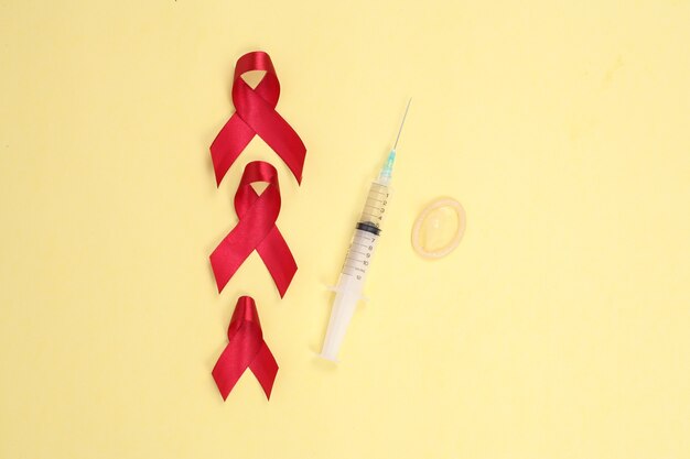 Red ribbon and medical device symbol against HIV isolated on yellow background